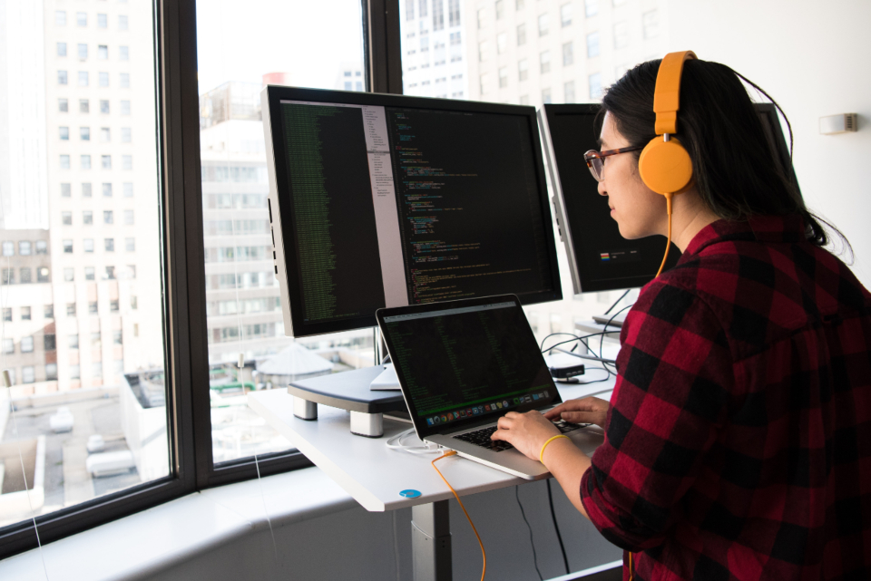 Người viết code trên nhiều màn hình, minh họa cho việc tự động hóa Excel bằng VBA thay vì Power Query