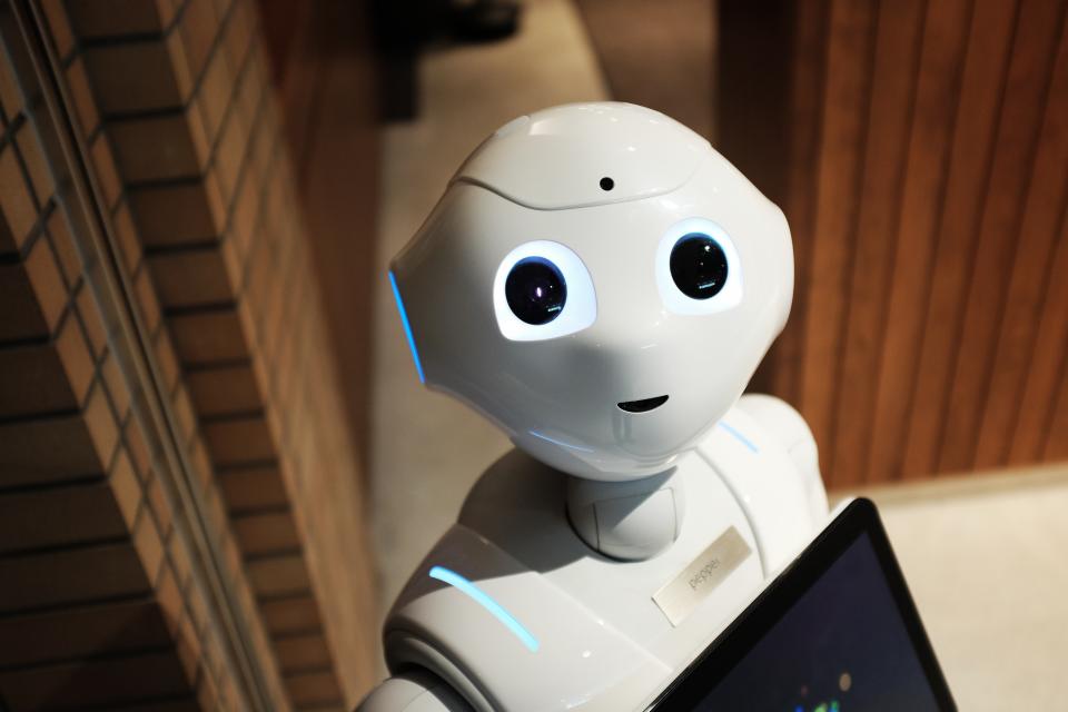 Robot dịch vụ màu trắng cầm màn hình cảm ứng, minh họa cho việc dùng AI để phân tích số liệu